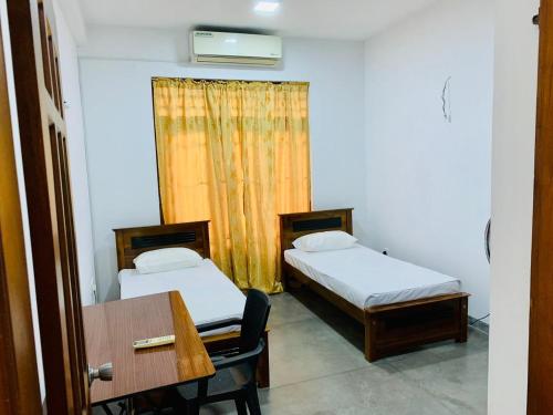 Zimmer mit 2 Betten, einem Schreibtisch und einem Tisch in der Unterkunft Privet Home Stay in Wattala