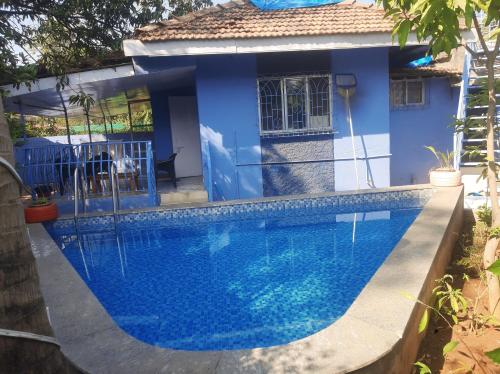 a swimming pool in front of a blue house at Blue Lagoon 2bhk in Lonavala