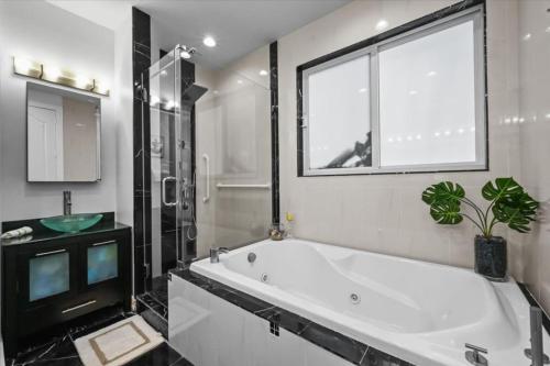a bathroom with a large white tub and a window at Casa del Sol - Heated Saltwater Pool - Waterfront - Paddle Boards in Fort Lauderdale