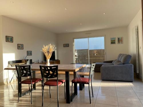 a dining room with a table and chairs and a couch at 1100-Maison au cœur du village de Planguenoual. in Planguenoual