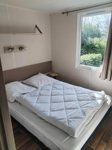 a bedroom with a white bed with a window at Mobil-Home 6 personnes avec TV et clim N' B025 in Boofzheim