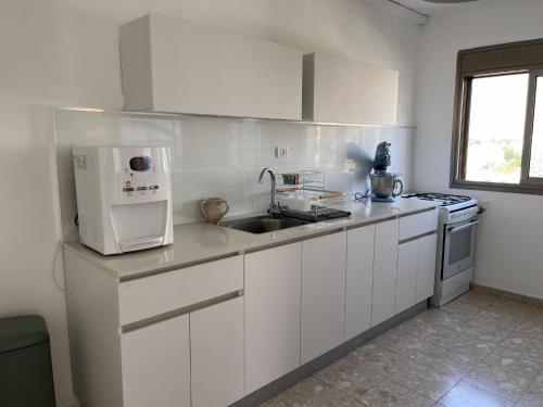a white kitchen with a sink and a microwave at Kosher for Passover Beachfront Apartment in Netanya
