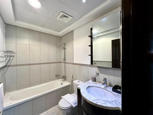 La salle de bains est pourvue d'un lavabo, d'une baignoire et de toilettes. dans l'établissement Lux BnB Travo Tower I Private Garden I Lake View, à Dubaï
