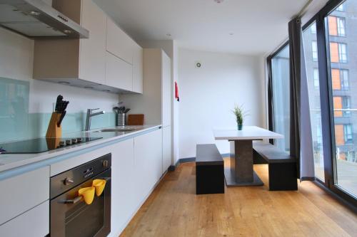 uma cozinha com um lavatório e uma mesa num quarto em Canning Town by Viridian Apartments em Londres