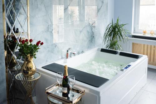 a bathtub in a white bathroom with a sink at Apartament Jacuzzi in Gdynia