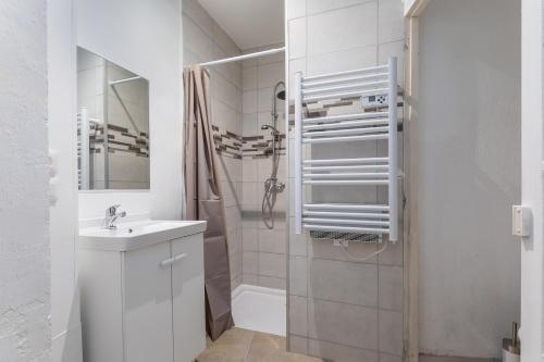 une salle de bain blanche avec un lavabo et une douche dans l'établissement Studio proche de Béziers centre, à Béziers