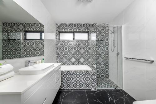 a white bathroom with a sink and a shower at Sensational New Townhouse in Canberra