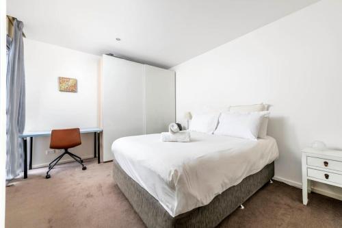 a white bedroom with a bed and a desk at London Circuit - City Hideaway in Canberra