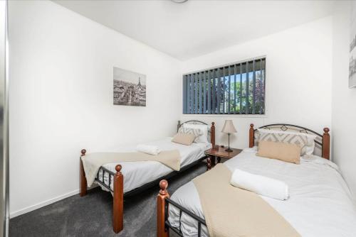 two beds in a room with white walls at Awesome family House & Studio in Narrabundah