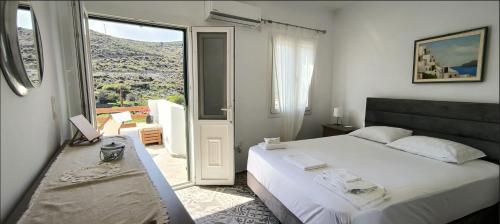 ein Schlafzimmer mit einem großen Bett und einem großen Fenster in der Unterkunft Kythneria in Kythnos