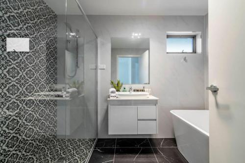 y baño con ducha, lavabo y bañera. en Gorgeous Hawker Townhouse en Canberra