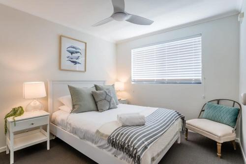 a bedroom with a bed and a chair and a window at Beachfront Oasis with Private Rooftop Retreat in Marcoola