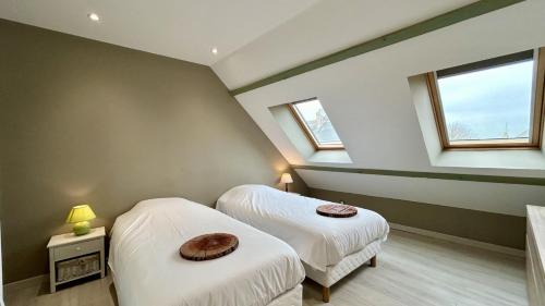 deux lits dans une chambre avec deux fenêtres dans l'établissement La Hutte, au Crotoy