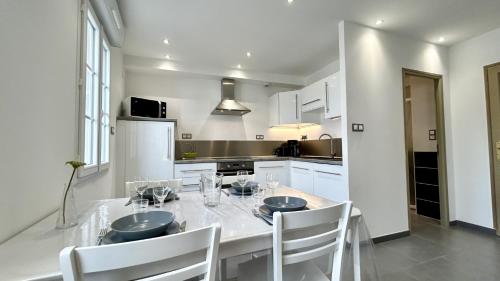 - une cuisine blanche avec une table à manger et des chaises dans l'établissement La Hutte, au Crotoy