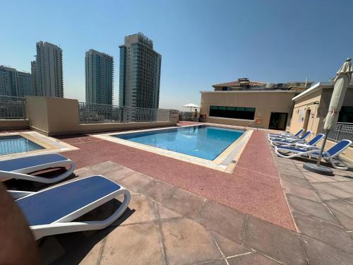 a swimming pool on the roof of a building with lounge chairs at Lux BnB I Una Tower I Lakes View in Dubai