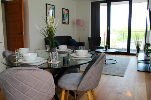 a dining room with a glass table and chairs at Canning Town by Viridian Apartments in London