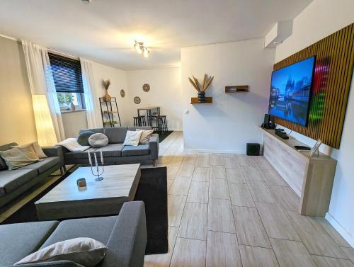 a living room with a couch and a tv on a wall at BesTime - 5 Schlafzimmer, Wohnzimmer, Küche, Waschtrockner, Terrasse, Smart-TVs, Netflix, Tischfußball in Wildeshausen