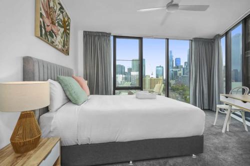 um quarto com uma grande cama branca e vista para a cidade em Modern Comfort Meets City Skyline em Melbourne