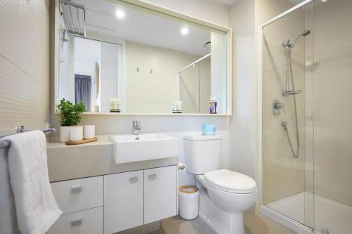 a bathroom with a toilet and a sink and a shower at Modern Comfort Meets City Skyline in Melbourne