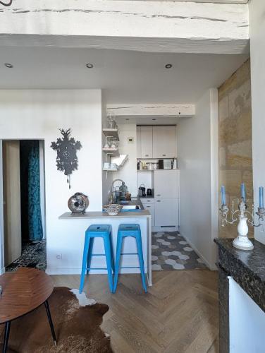 une cuisine avec une table et deux tabourets bleus dans l'établissement Appartement de charme sous les toits avec vue sur la Garonne, à Bordeaux