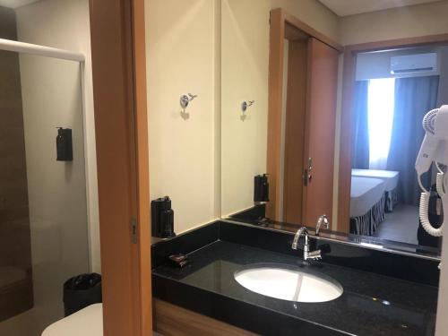 a bathroom with a sink and a large mirror at Apto Thermas Resort São Pedro in São Pedro