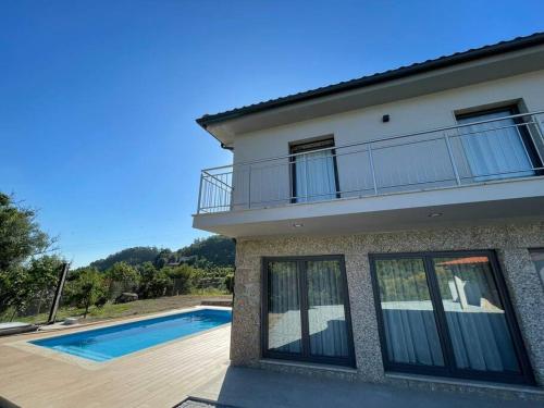 a house with a balcony and a swimming pool at Casa do Canastro in Terras de Bouro