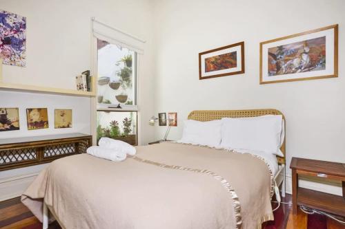 um quarto branco com uma cama e uma janela em Carlton Heritage Home - Explore Melbourne's Heart em Melbourne