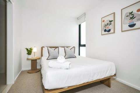 a bedroom with a white bed and a table at Stylish Urban Retreat with Spectacular Views and Prime Location in Melbourne