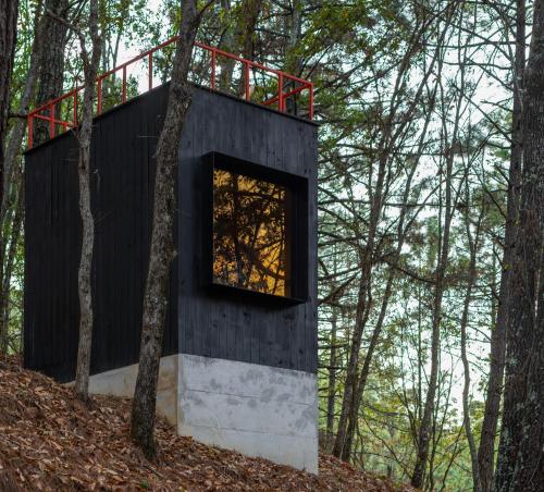 a black house in the woods with a window at Concentrico by The Outlands in Ciénaga