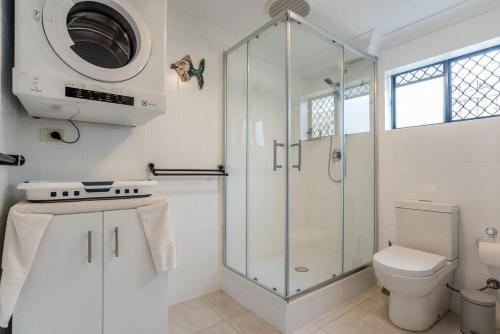a white bathroom with a shower and a toilet at Seaside Serenity at Plumeria Place in Brisbane