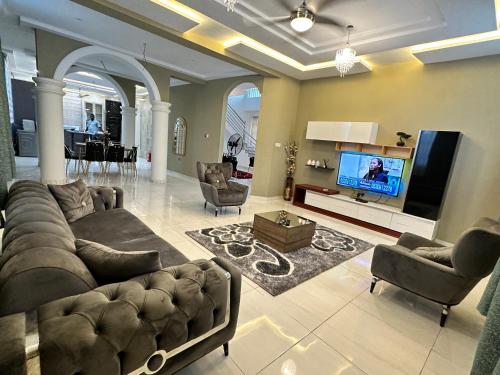 a living room with a large couch and a tv at Nanani Villa - Harmonious Paradise in Kumasi