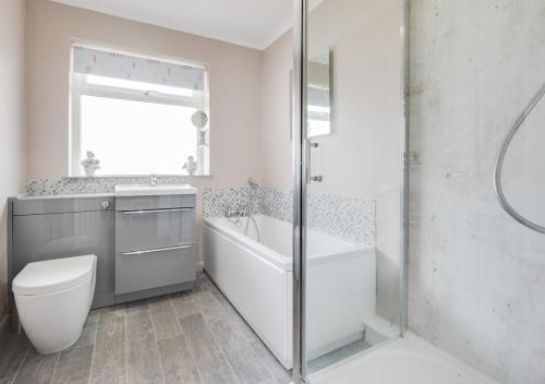 een badkamer met een bad, een toilet en een wastafel bij LAmourette in Bacton