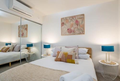 a white bedroom with two beds and two lamps at Stylish Apartment with Rooftop Pool in Brisbane