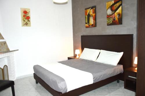 a bedroom with a bed and two paintings on the wall at Helios Rooms in Flumini di Quartu