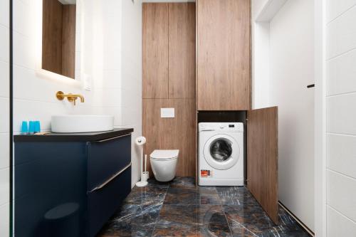 a bathroom with a washing machine and a sink at Wieniawskiego Chic Apartment in Łódź