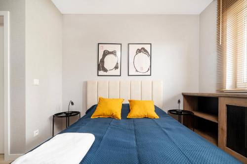 a bedroom with a bed with blue sheets and yellow pillows at Wieniawskiego Chic Apartment in Łódź