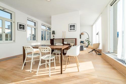 High-class rooftop apt. with spacious terrace في براغ: غرفة معيشة بيضاء مع طاولة وكراسي خشبية