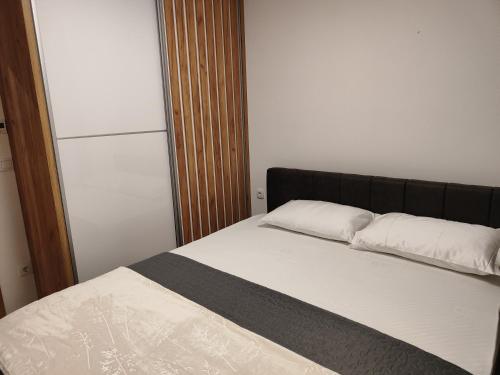 ein Bett mit zwei Kissen auf einem Zimmer in der Unterkunft Apartmani Sanja in Teslić
