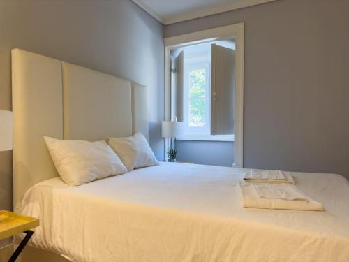 sypialnia z dużym białym łóżkiem i oknem w obiekcie Home Mais Mastro w Lizbonie