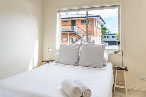 1 dormitorio con cama blanca y ventana grande en Modern 2BR in Ashgrove, en Brisbane