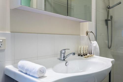 Baño blanco con lavabo y espejo en Modern Victorian Holiday Home in Ashgrove en Brisbane