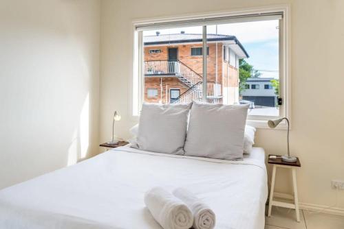 1 dormitorio con cama blanca y ventana en Modern Victorian Holiday Home in Ashgrove en Brisbane