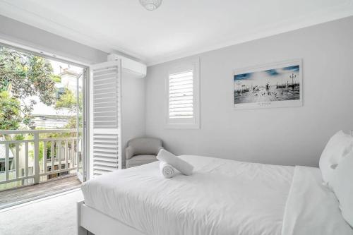 a white bedroom with a bed and a chair at Stylish Home in the heart of Newtown in Sydney