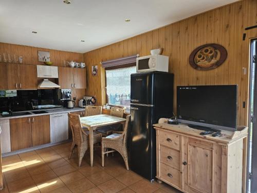 uma cozinha com um frigorífico preto e uma mesa com uma televisão em Grabówka em Nadole