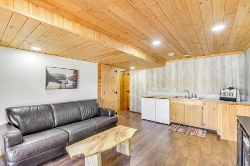 a living room with a leather couch and a kitchen at Lakefront Park Rapids Cabin with Decks and Boat Dock! in Park Rapids