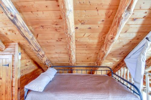 a bed in a log cabin with a ceiling at Lakefront Park Rapids Cabin with Decks and Boat Dock! in Park Rapids
