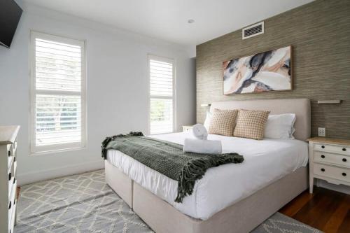 a bedroom with a large white bed and two windows at Rodd Point Luxury Haven: Waterfront Elegance with BBQ Terrace in Sydney