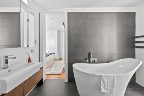 a bathroom with a white tub and a sink at Rodd Point Luxury Haven: Waterfront Elegance with BBQ Terrace in Sydney