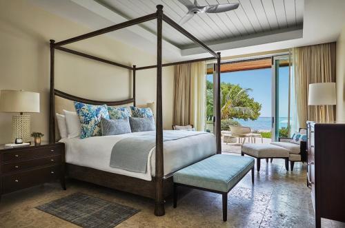 a bedroom with a canopy bed and a patio at Oil Nut Bay in Virgin Gorda