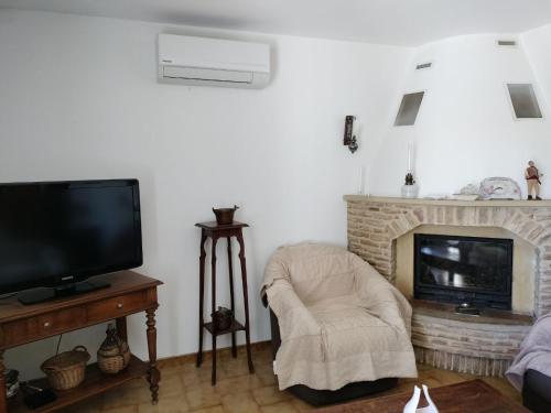 uma sala de estar com uma televisão, uma cadeira e uma lareira em Les oliviers du pradon em Lagarde-Paréol